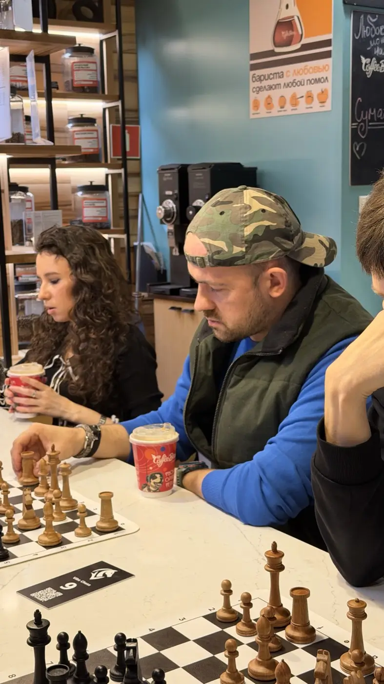 Двое играют партию за столиком в Coffee Bean, рядом стаканы с кофе