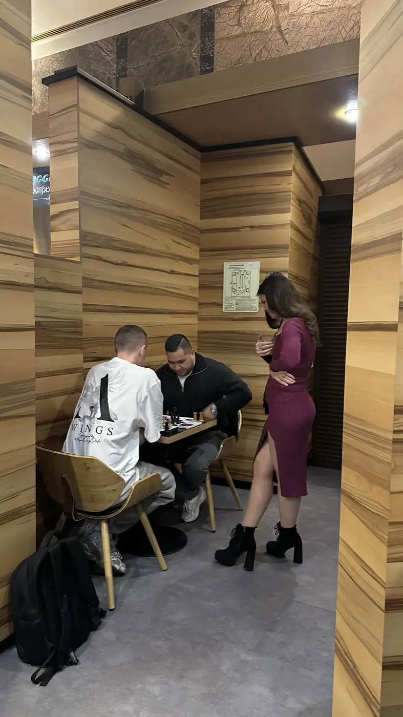 Двое играют партию, рядом стоит и наблюдает зритель