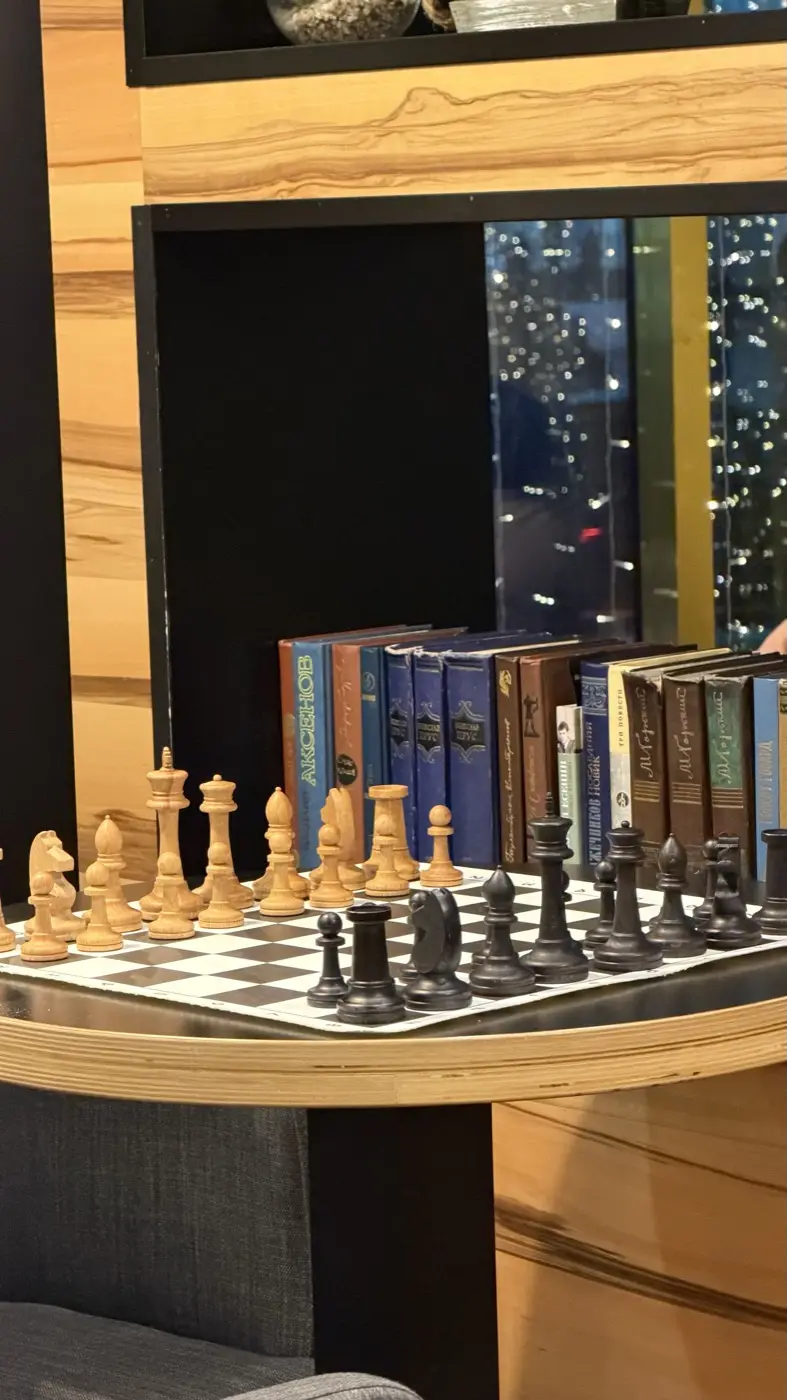 Деревянные фигуры крупным планом на фоне корешков книг