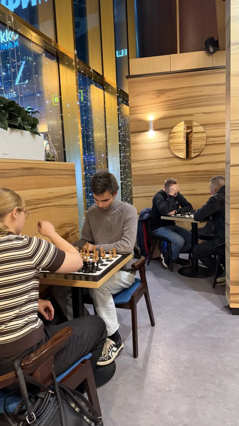 Партии за двумя столами в Coffee Bean, за окном огни башен Москва-Сити