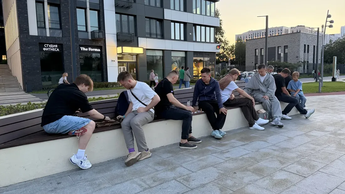 Компания играет в шахматы на набережной в Москве вечером