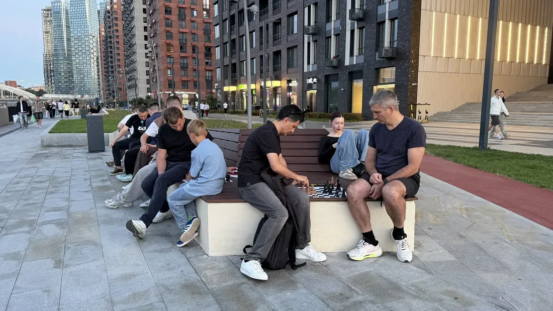 Компания играет в шахматы вечером на набережной